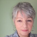Woman with short gray hair, hoop earrings.
