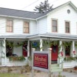 White house with porch and decorative greenery.